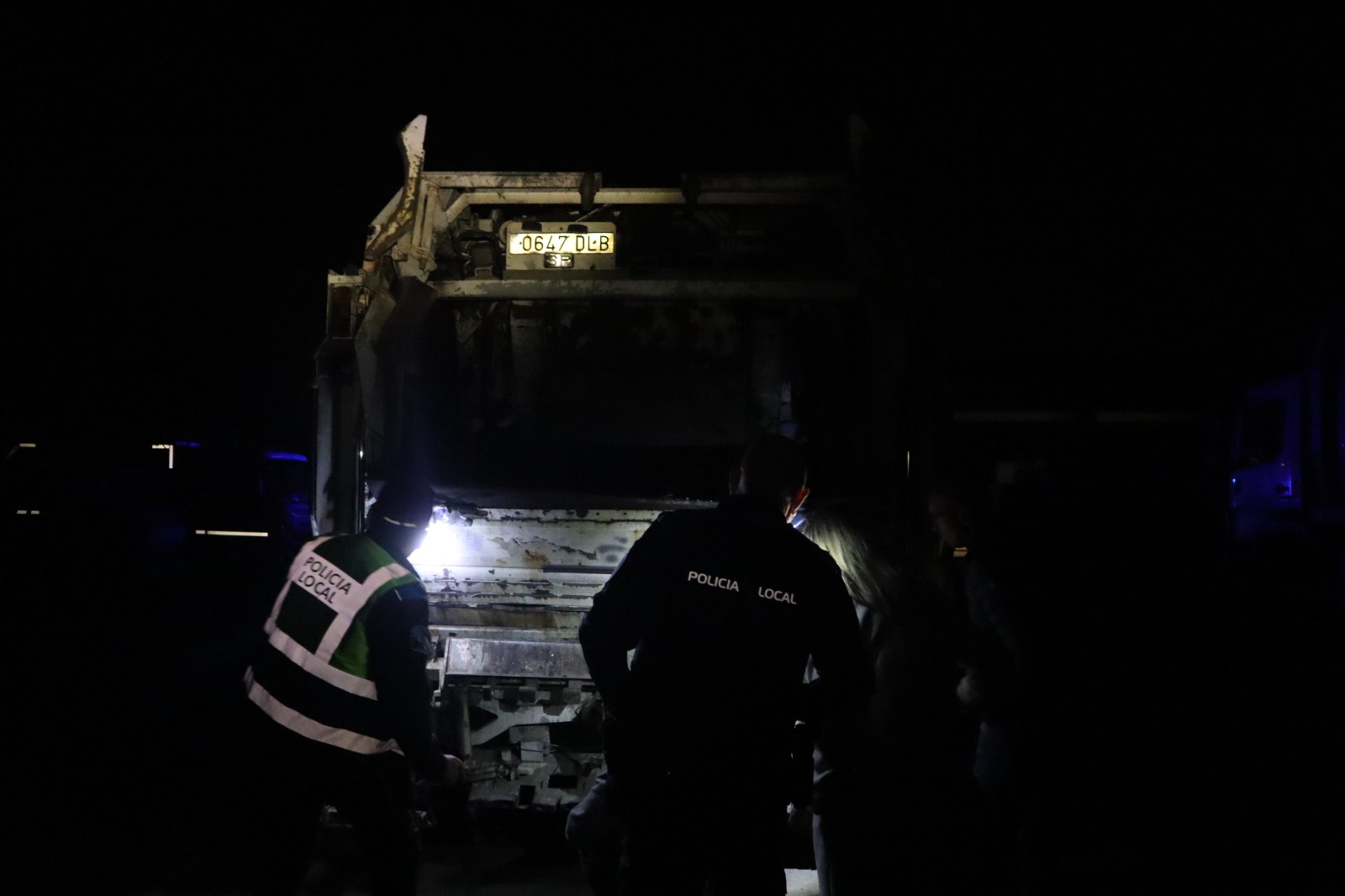 Axentes da policía local inspeccionando un dos camións danados